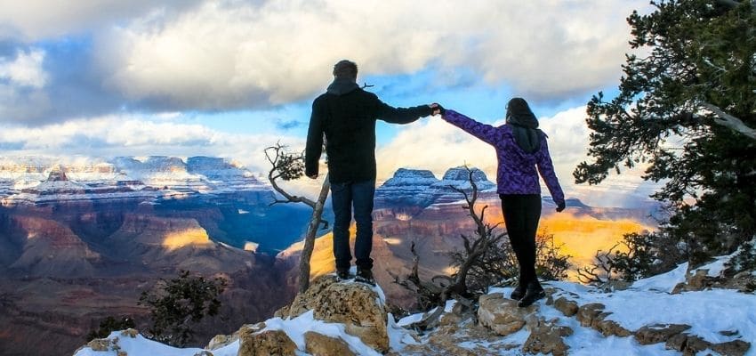 couple holding hands at grand canyon in winter snow
